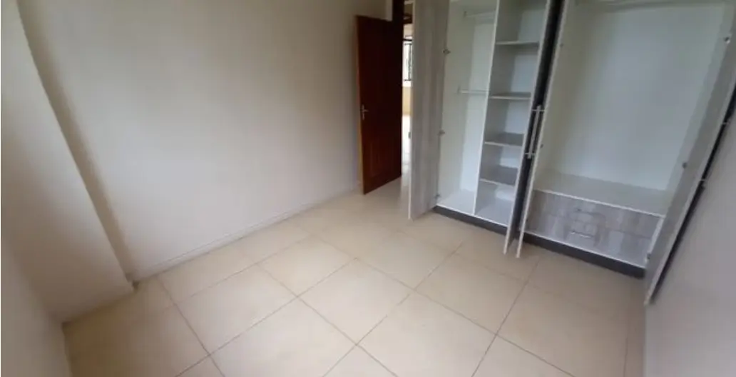 Unfurnished bedroom with tiled floor and built-in wardrobes