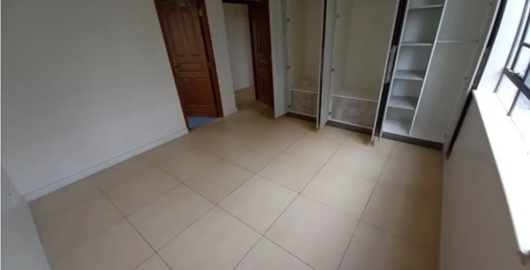 Spacious bedroom with tiled flooring and built-in wardrobes
