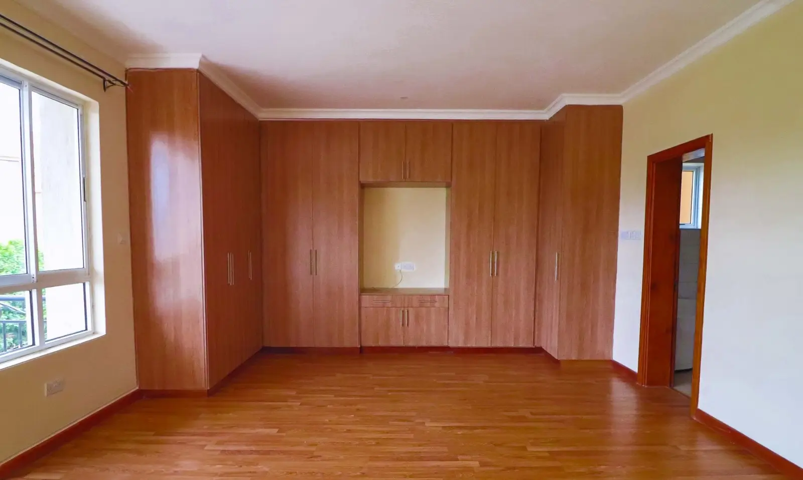 Spacious bedroom with wooden built-in wardrobes and hardwood floor
