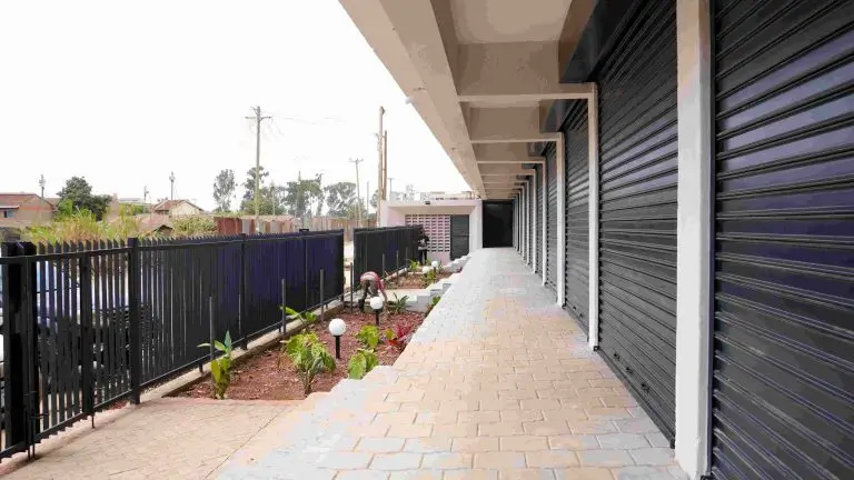 Covered parking area with roller shutters and landscaped perimeter