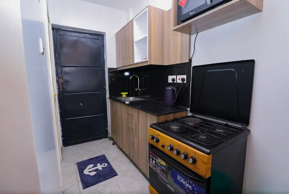 Compact kitchen with black countertops and yellow gas stove