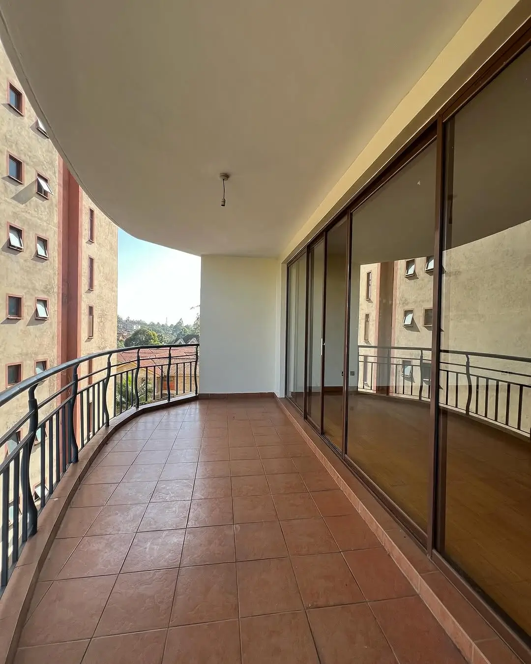 Spacious curved balcony with terracotta tiles and city views