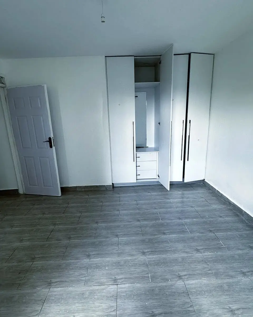 Spacious empty bedroom with built-in wardrobes and dark flooring