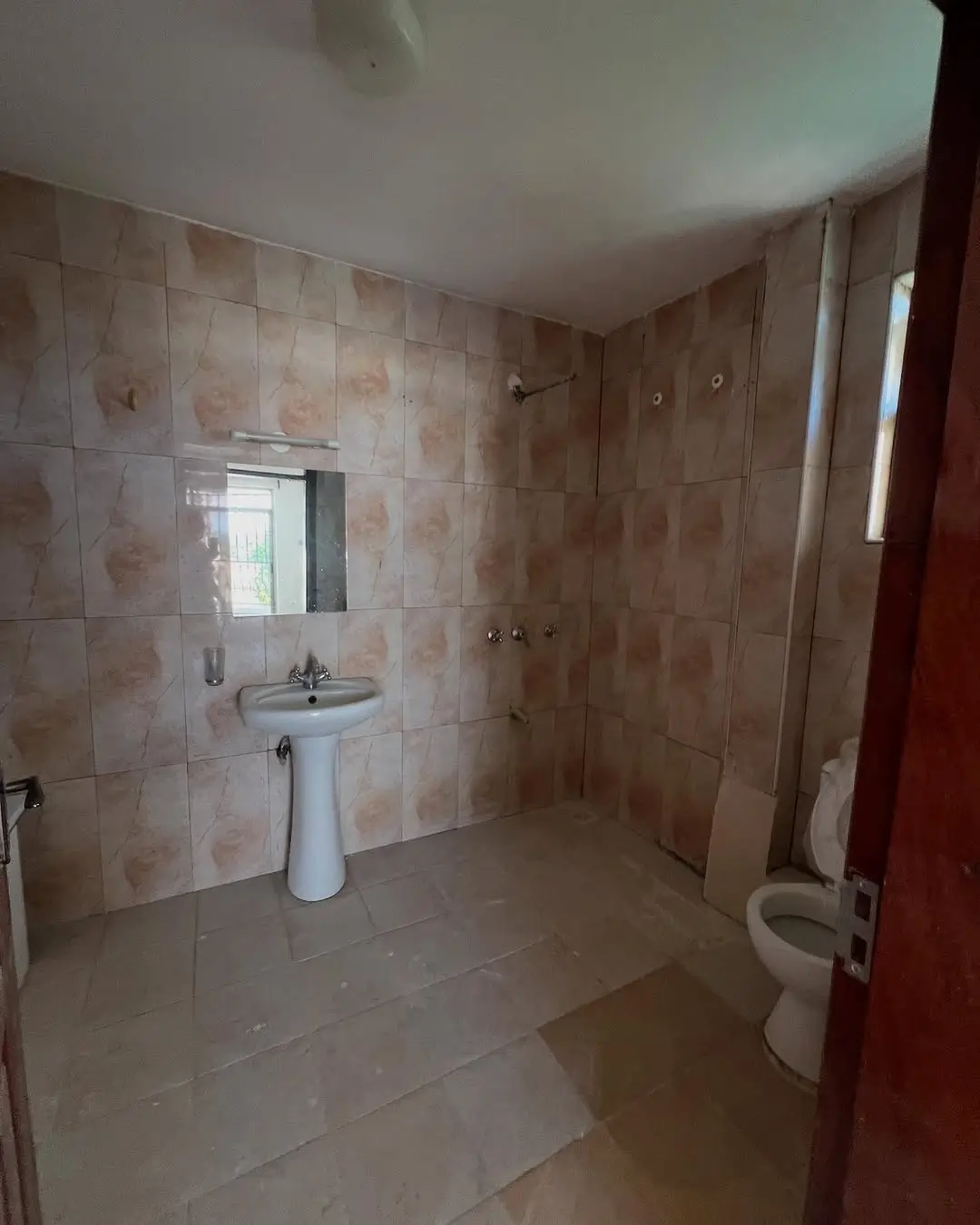 Spacious bathroom with pedestal sink and tiled walls
