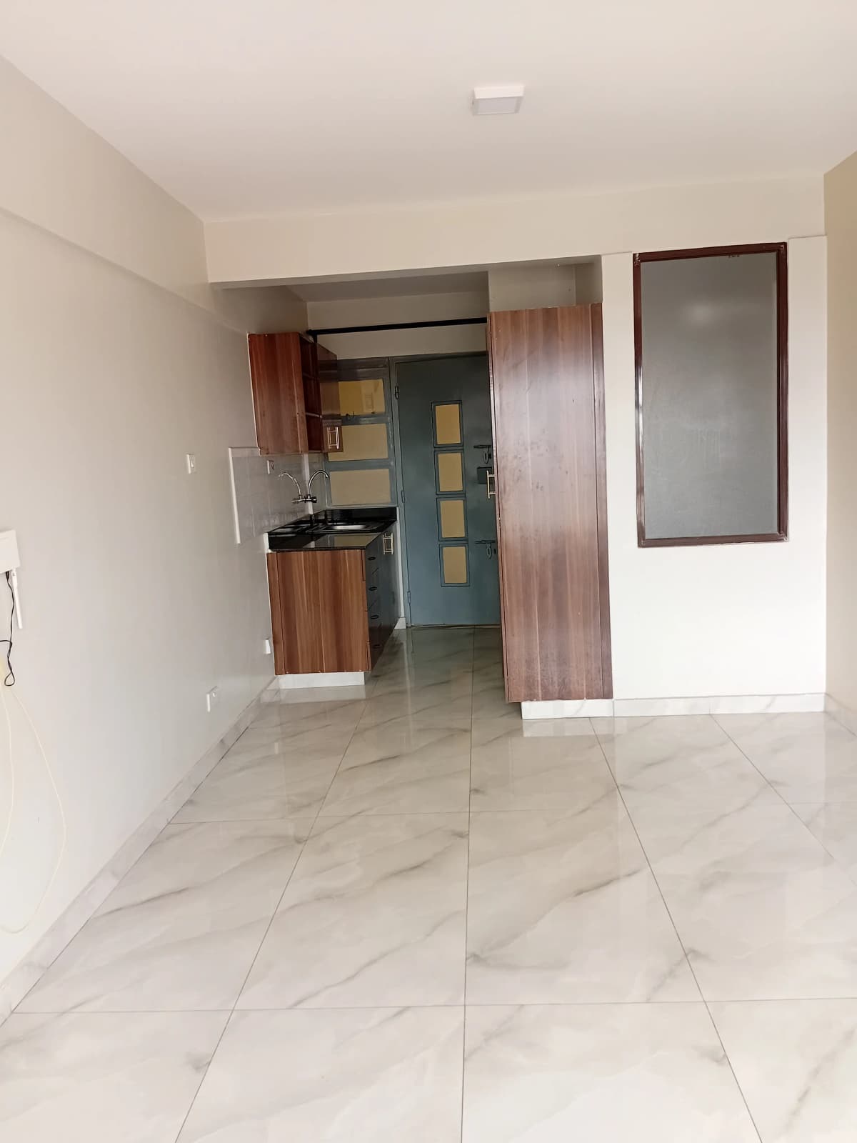 Open-plan living space with kitchen visible through doorway