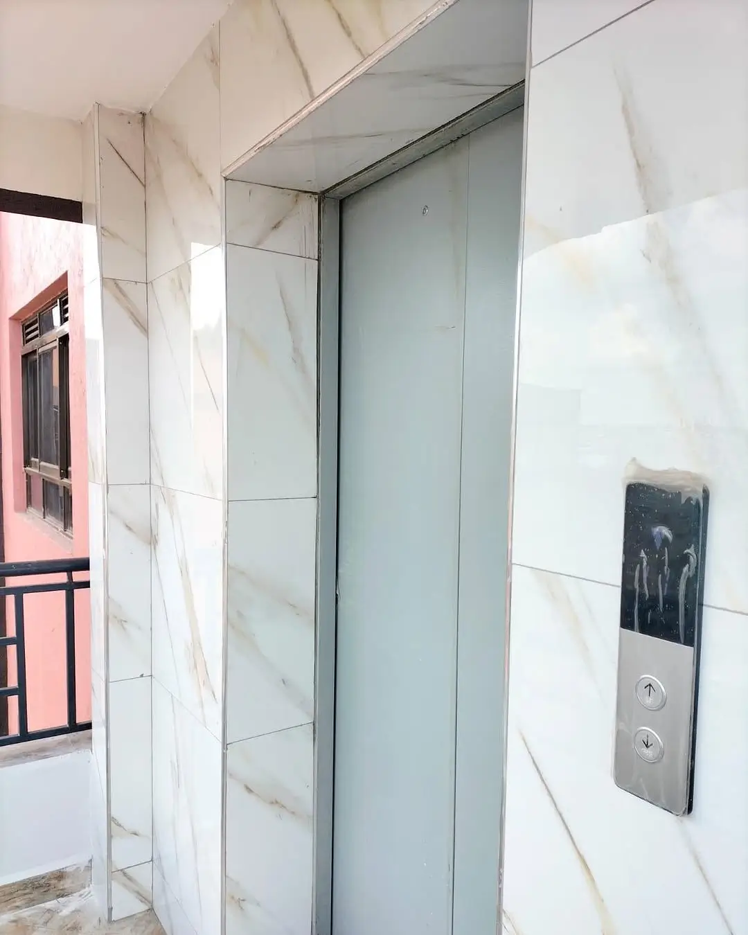 Modern elevator lobby with marble-effect tiling and glass doors