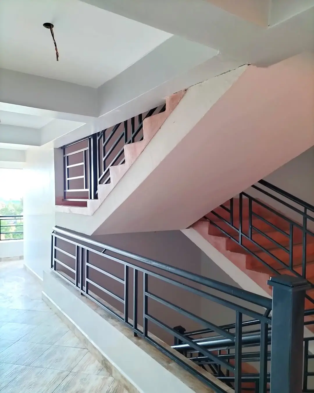Modern interior staircase with metal railings and pink accent wall