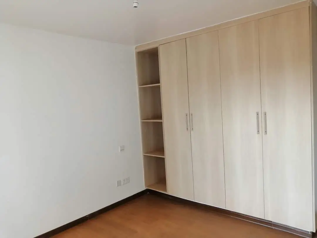 Empty bedroom with built-in wooden wardrobes and shelving
