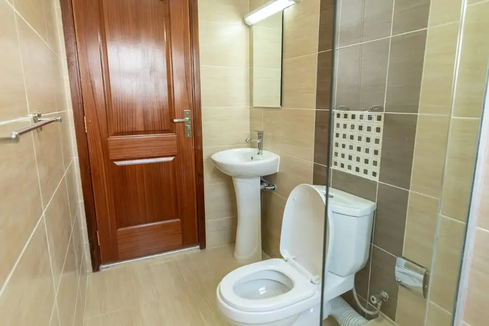 Compact bathroom with pedestal sink, toilet, and shower enclosure