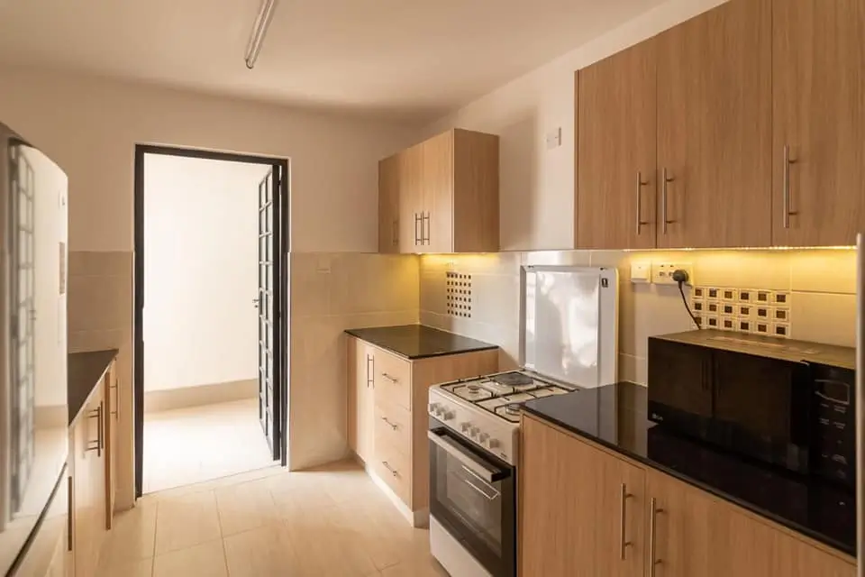 Modern kitchen with wooden cabinetry, stainless steel appliances, black countertop