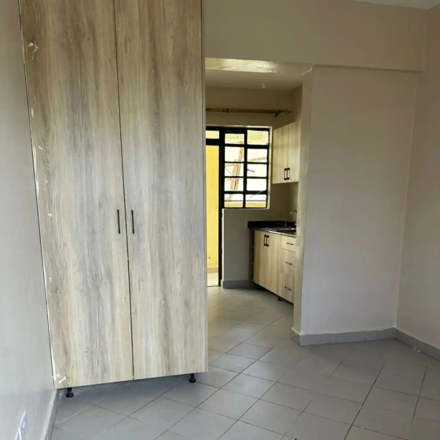 Open-plan kitchen with light wood cabinetry and tile flooring