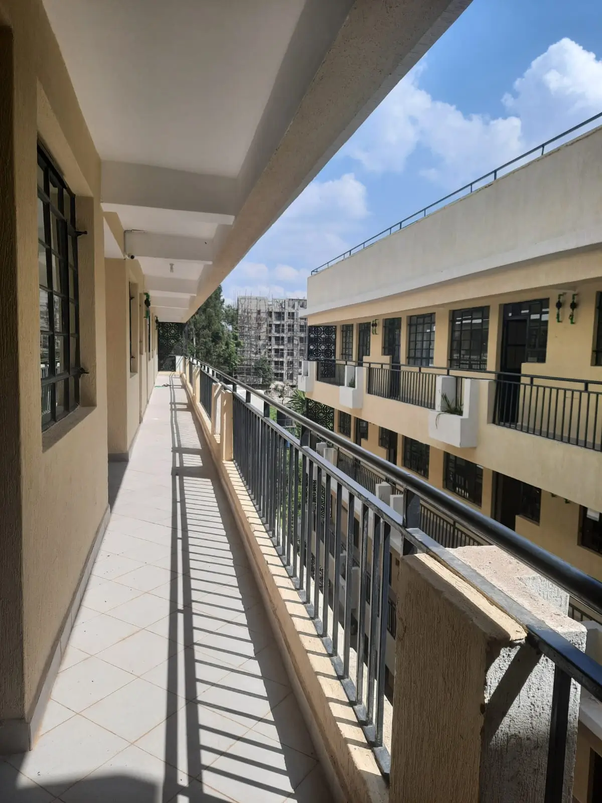 Long exterior balcony with metal railings overlooking compound
