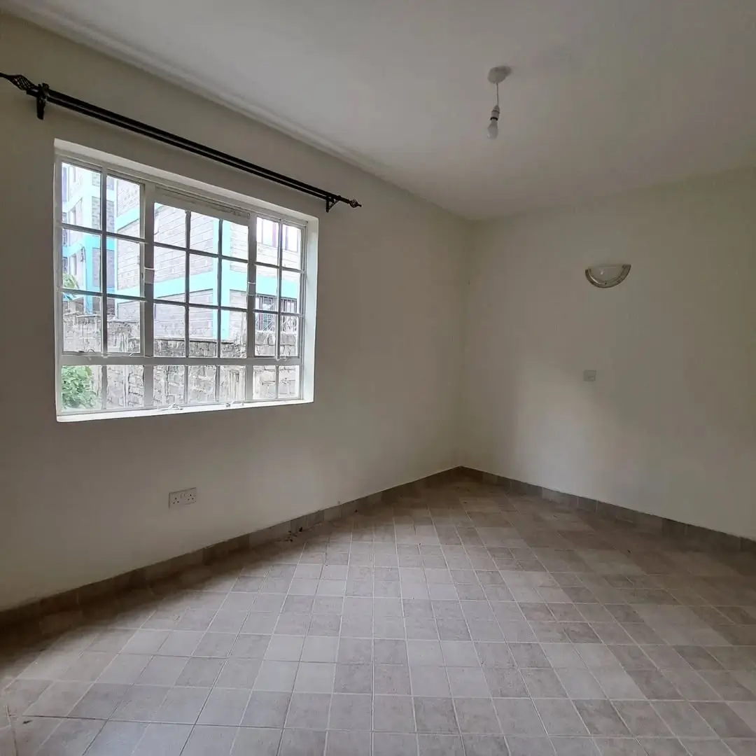 Spacious bedroom with large window and tiled flooring