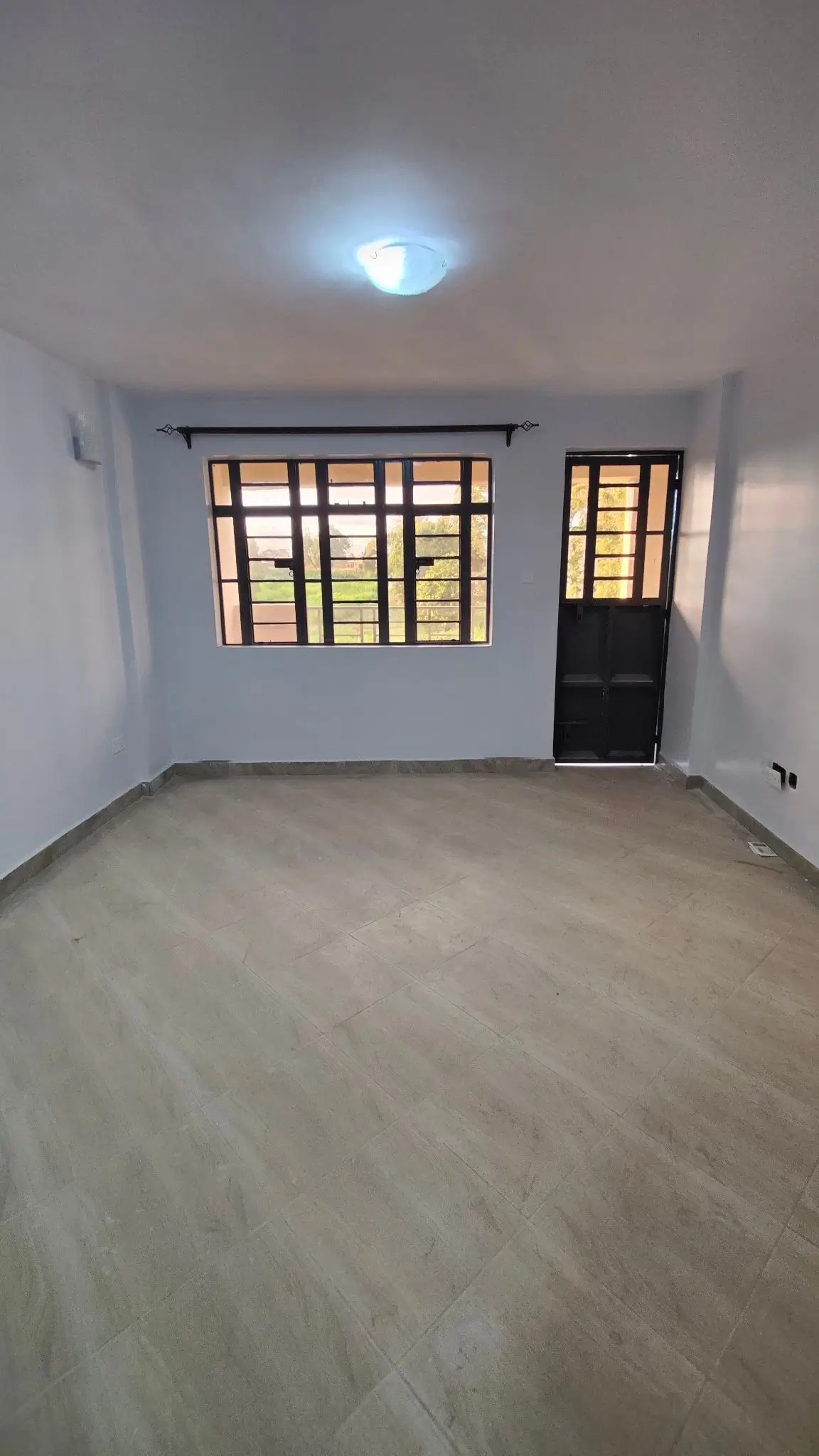 Empty bedroom with barred window and single door entry