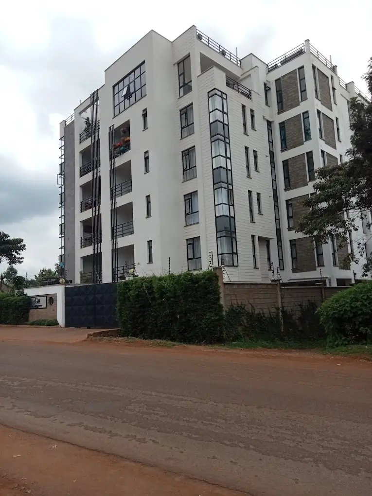 Modern multi-story residential apartment building with red soil compound