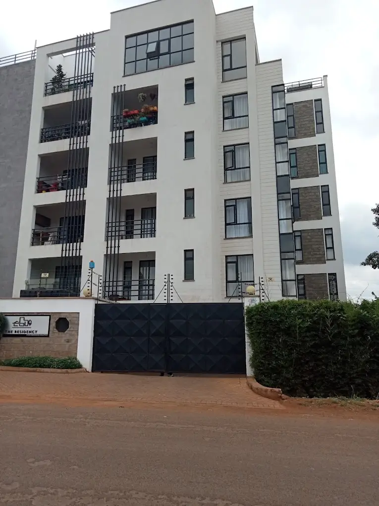 Modern multi-story residential building with balconies and gate