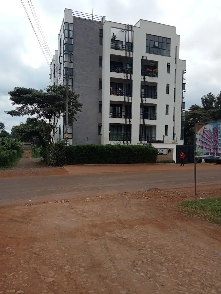 Modern multi-story residential building with balconies and compound grounds