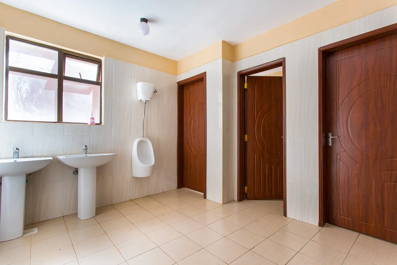 Clean bathroom with dual sinks, urinal, and tiled flooring