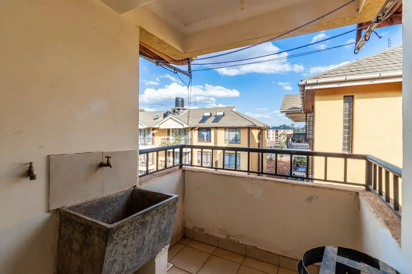 Covered balcony with metal railing overlooking residential neighborhood