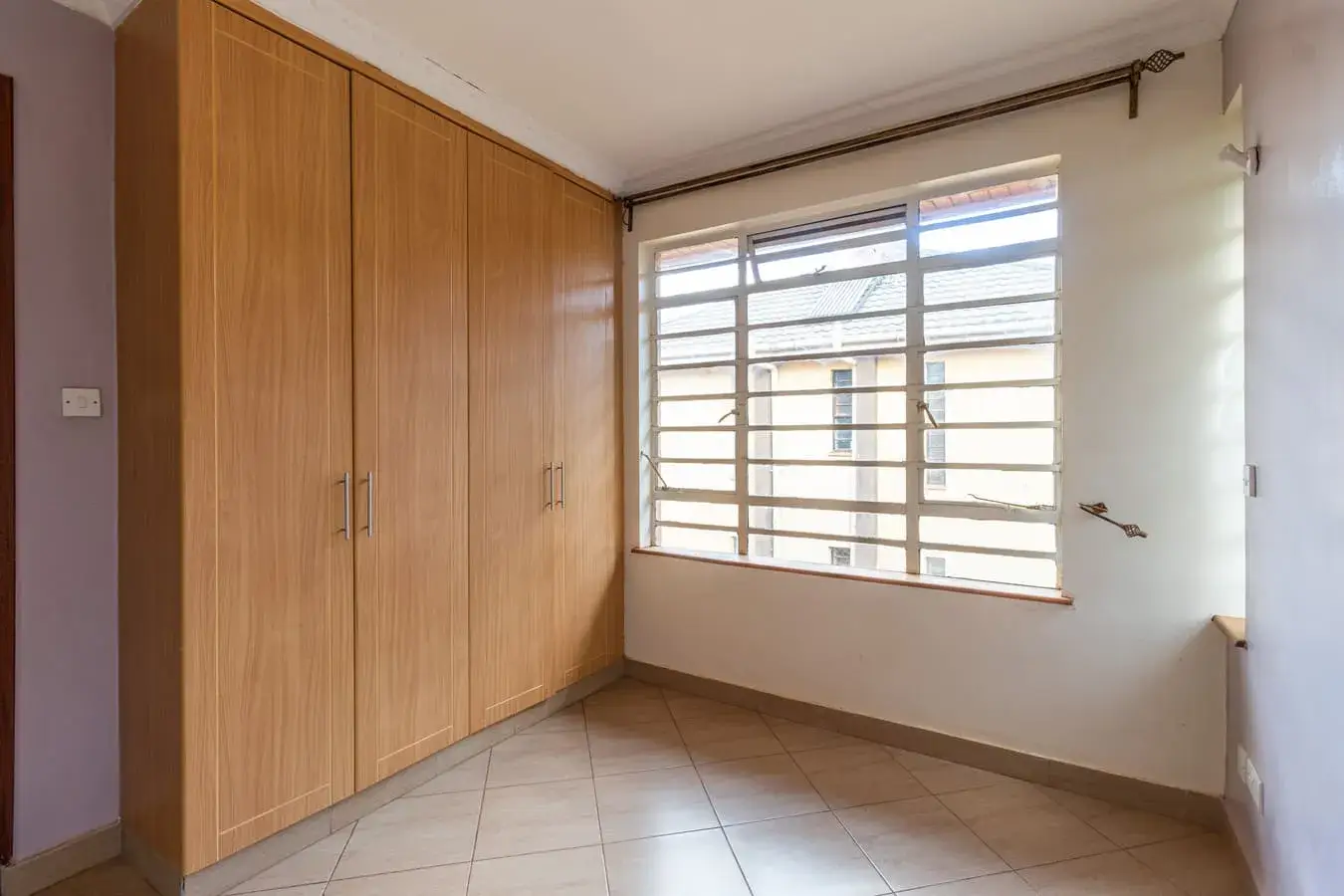 Bright bedroom with wooden wardrobe and barred windows