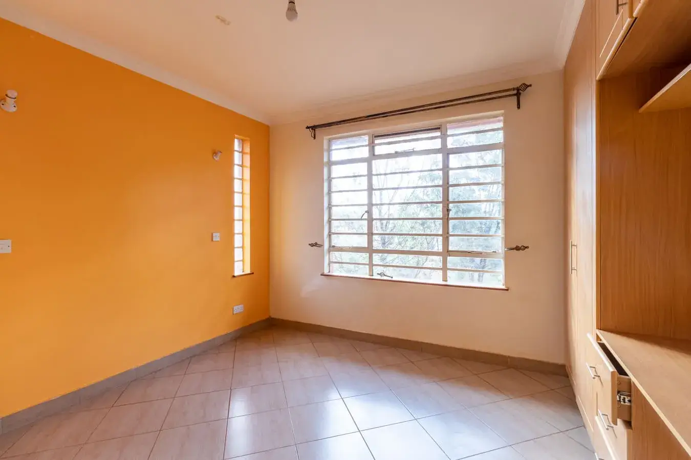 Bright bedroom with orange accent wall and large window