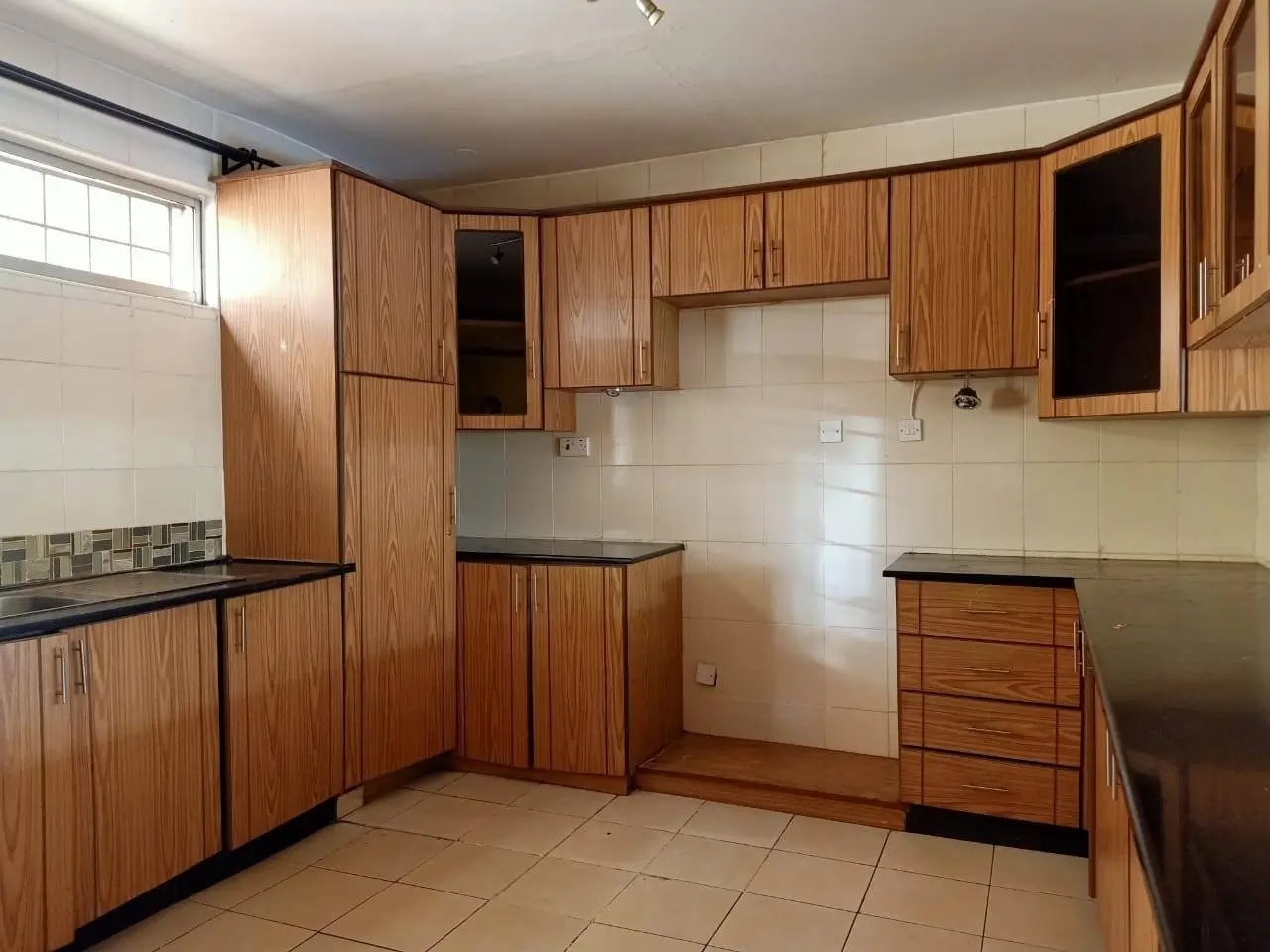 Spacious kitchen with wooden cabinetry and black countertops