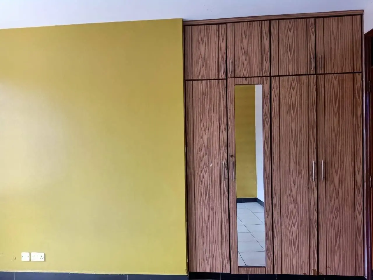 Bedroom with built-in wooden wardrobe and yellow accent wall