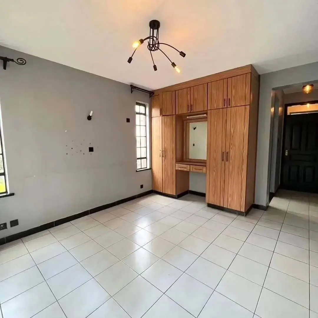Spacious bedroom with built-in wooden wardrobe and tiled flooring