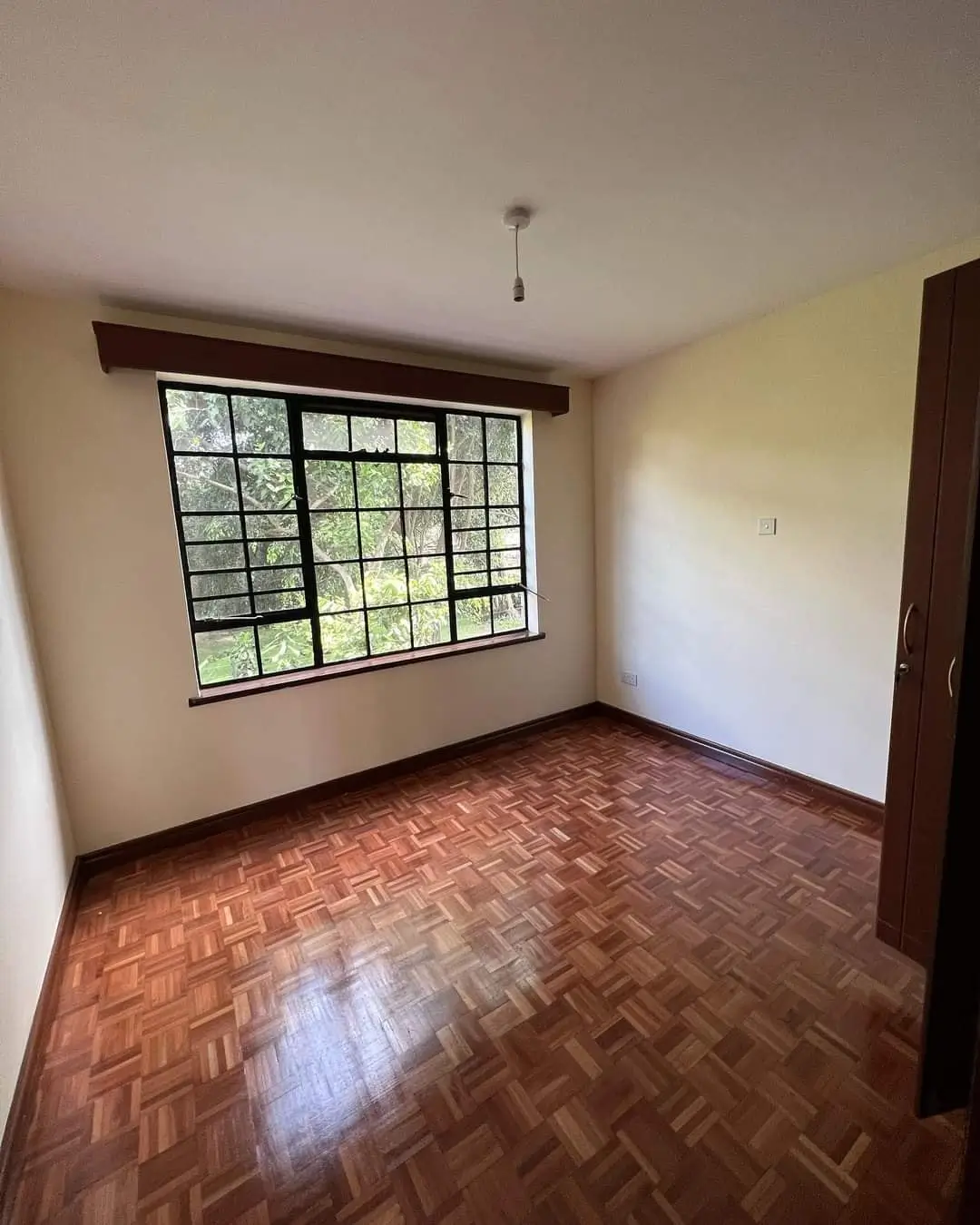 Bright bedroom with herringbone wood floors and barred window