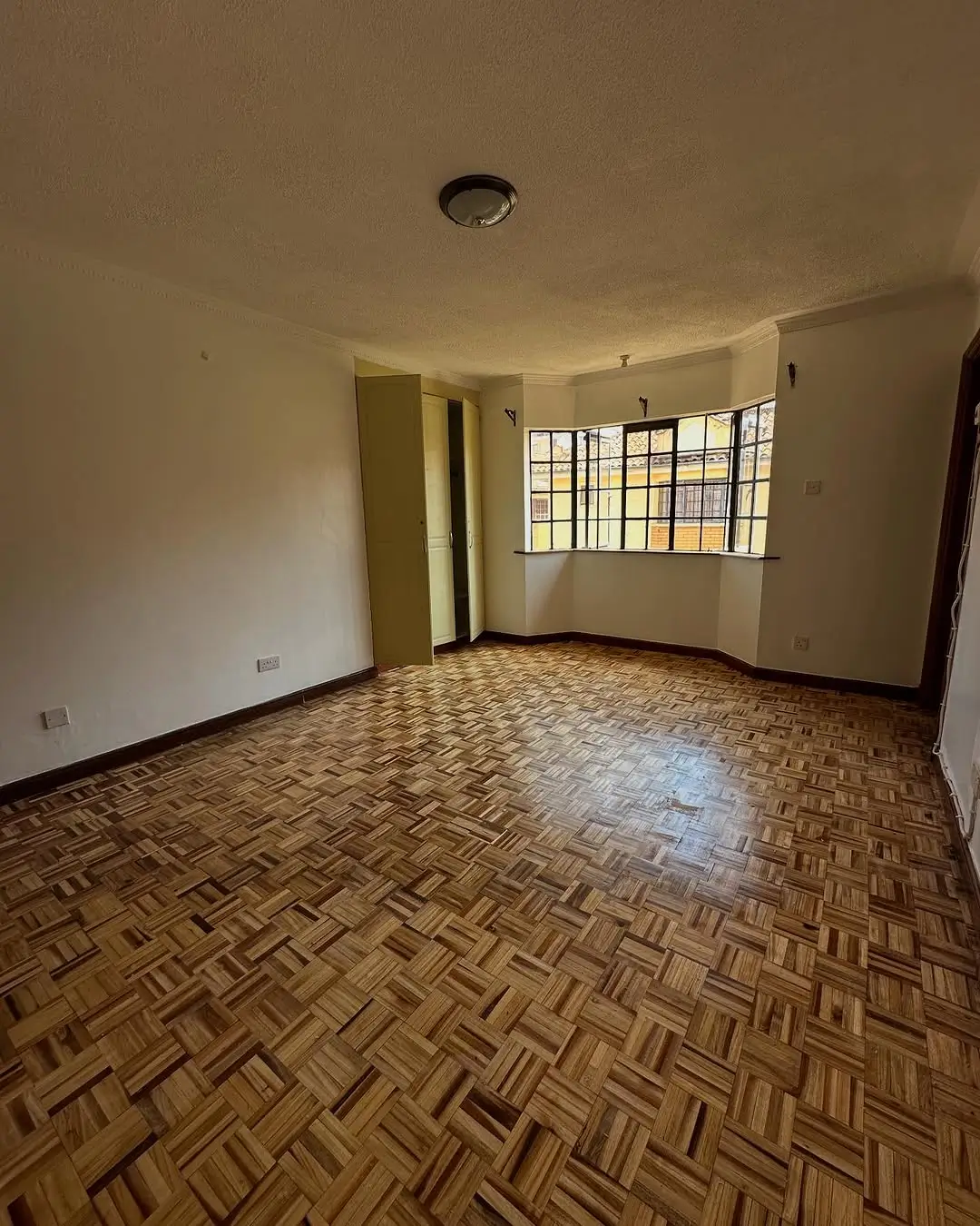 Spacious living room with herringbone parquet flooring and natural light