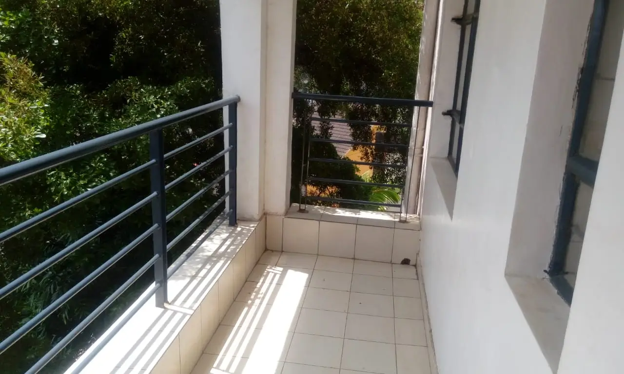 Tiled balcony with metal railing overlooking green garden