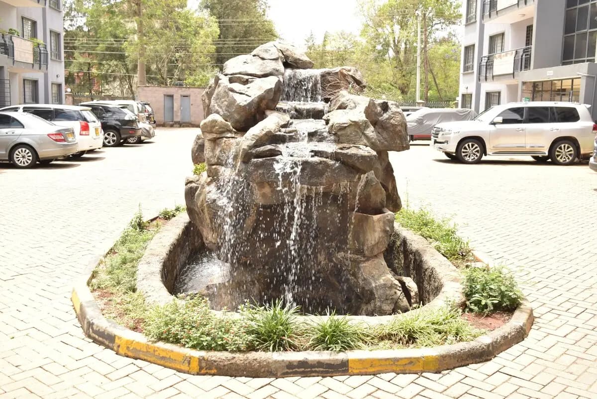Compound courtyard with decorative rock fountain and parked vehicles