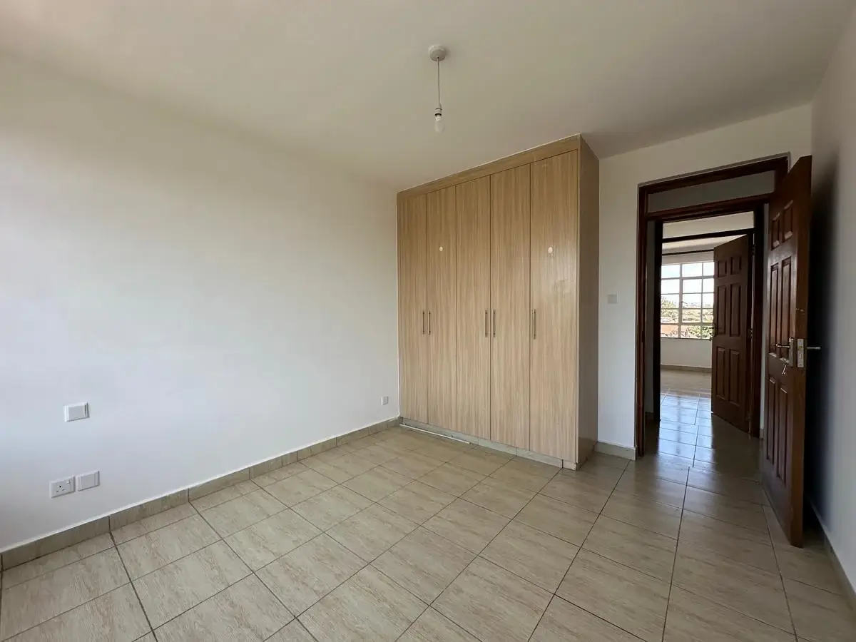 Spacious bedroom with wooden built-in wardrobe and tiled flooring