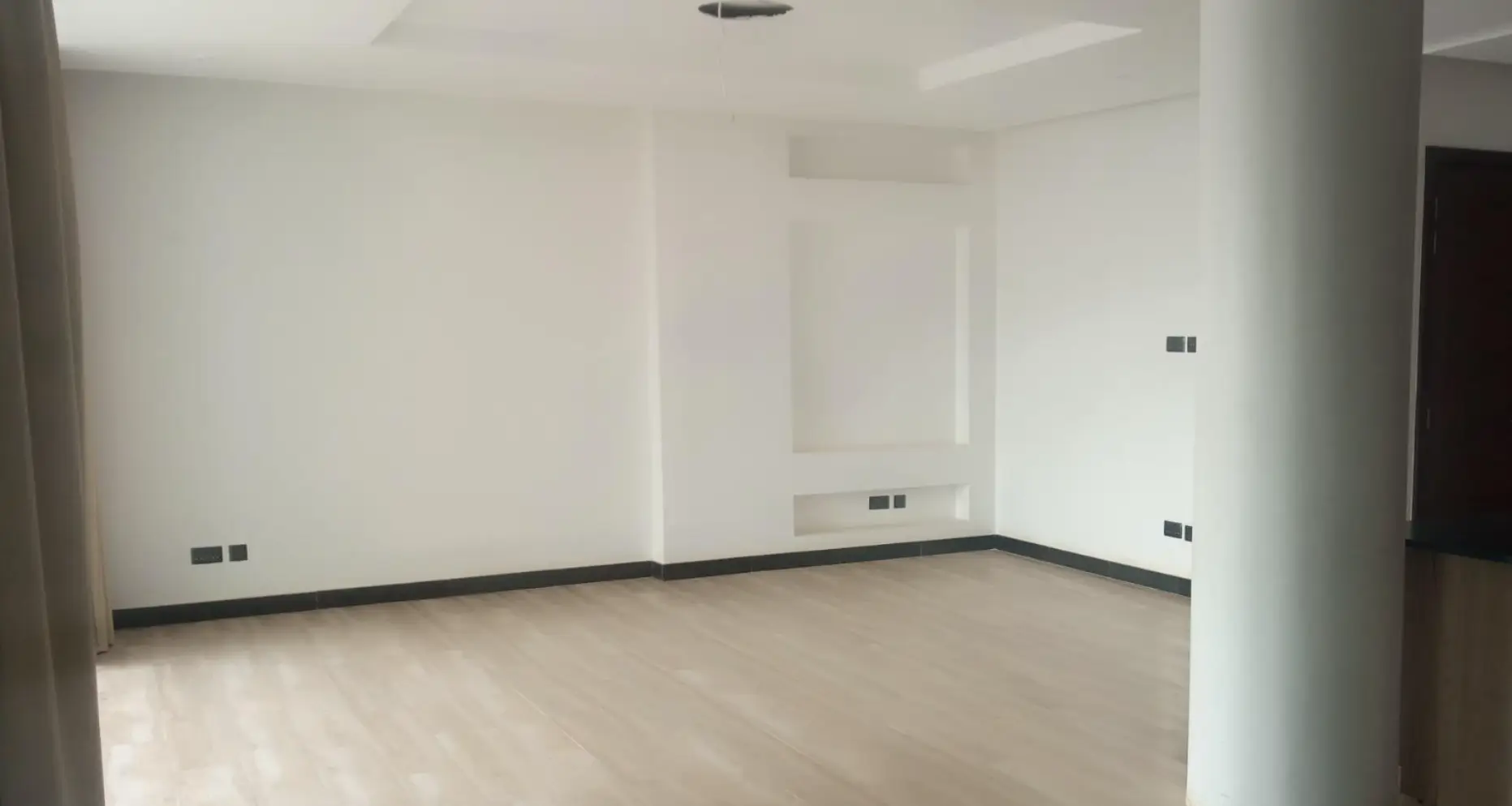 Spacious empty living room with pillar support and neutral finishes