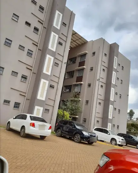Multi-story residential building with paved parking lot and vehicles