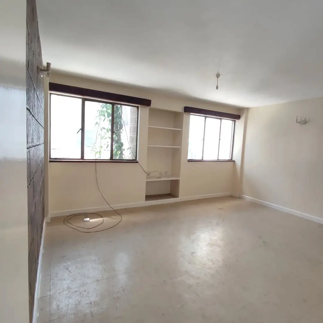 Spacious living area with dual windows and built-in shelving
