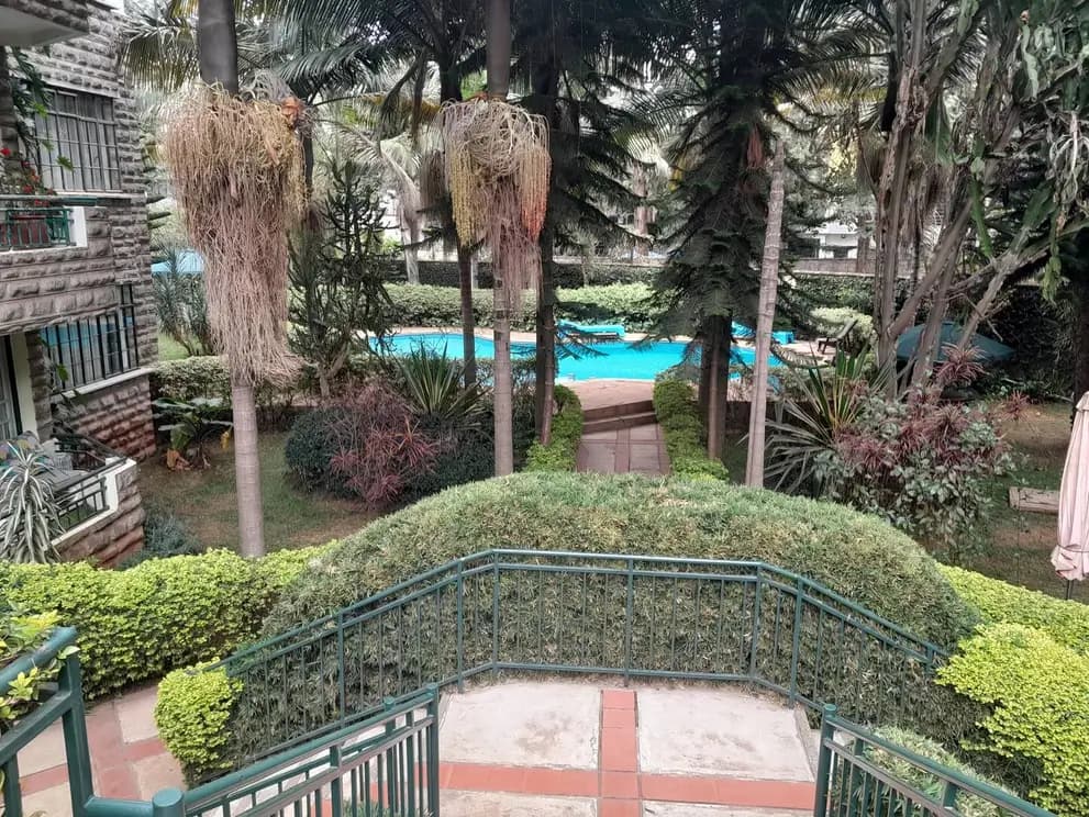 Balcony overlook of manicured gardens and swimming pool beyond