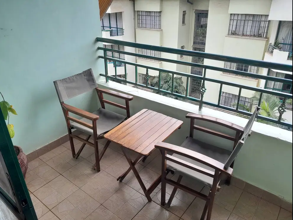 Compact balcony with wooden furniture and green railing