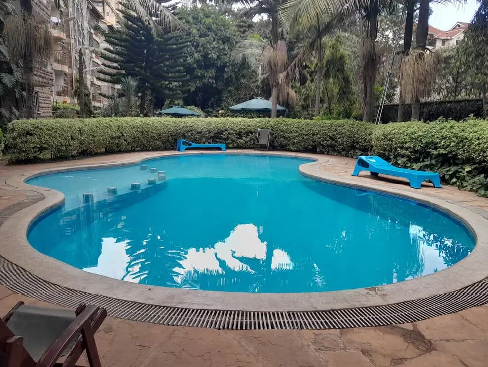 Large curved swimming pool with lounging deck and mature trees