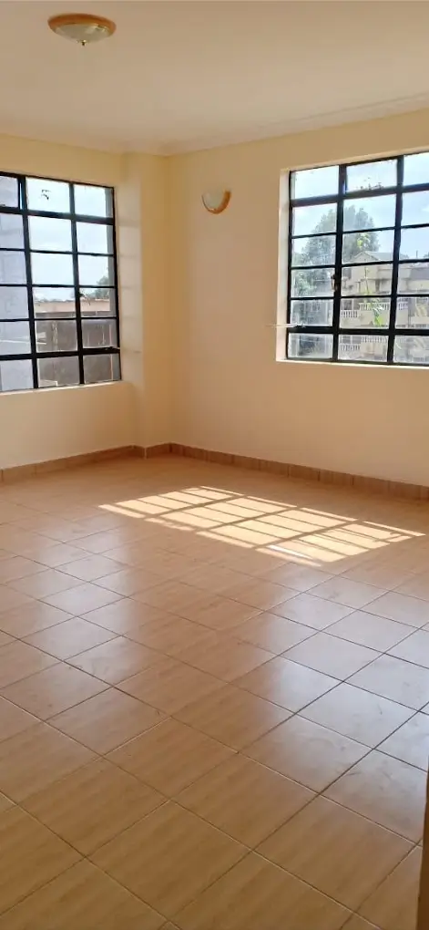 Spacious empty room with tile flooring and abundant natural light