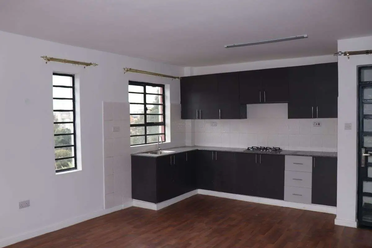 Modern L-shaped kitchen with black cabinets and white countertops