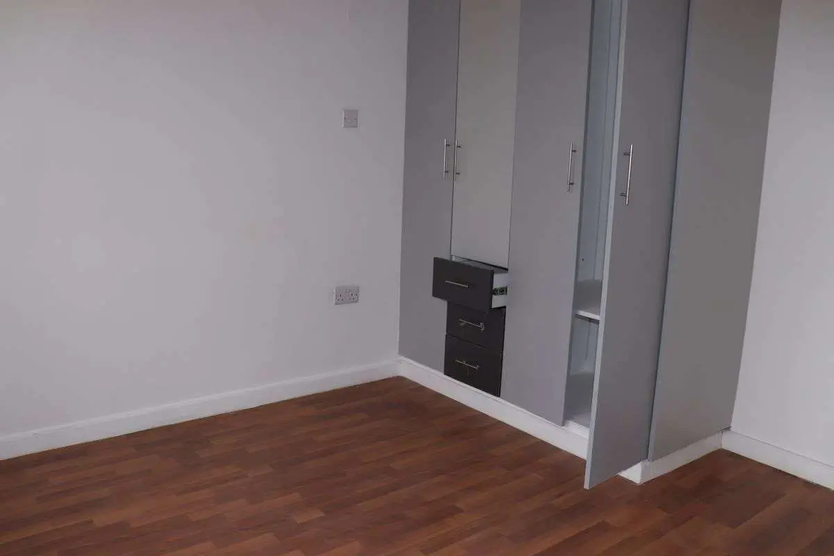 Empty bedroom with built-in wardrobes and wooden flooring