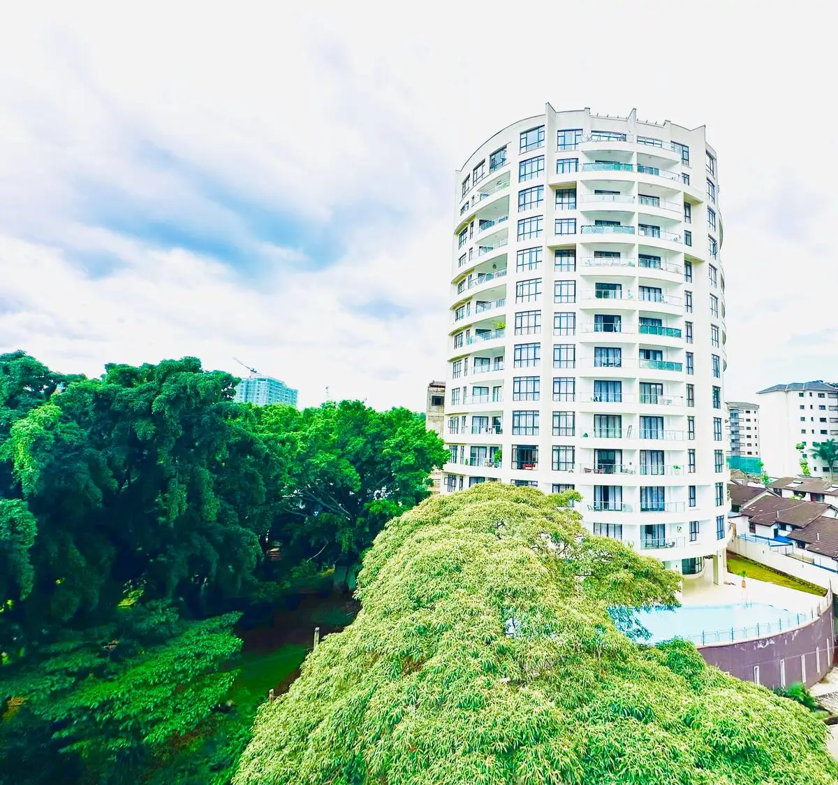 Urban apartment building with green surroundings and city skyline