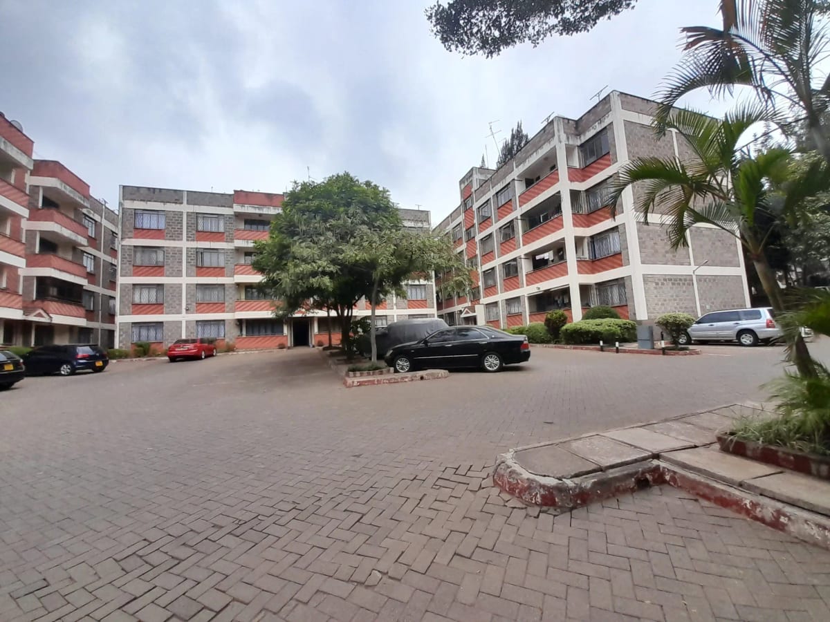 Multi-story residential compound with paved courtyard and parking