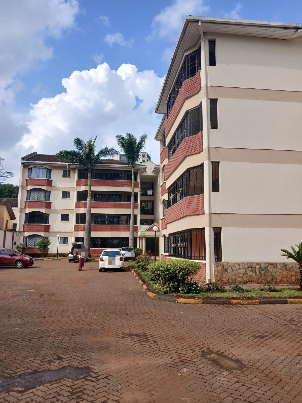 Multi-story residential building with brick paved compound entrance
