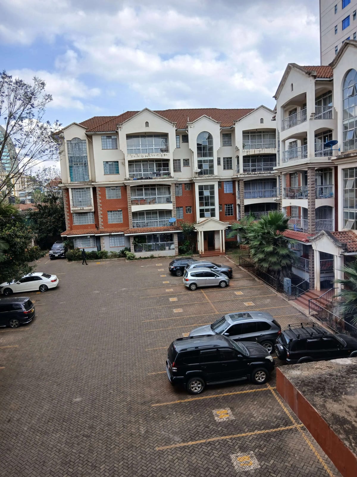 Residential compound parking lot with multiple vehicles and buildings
