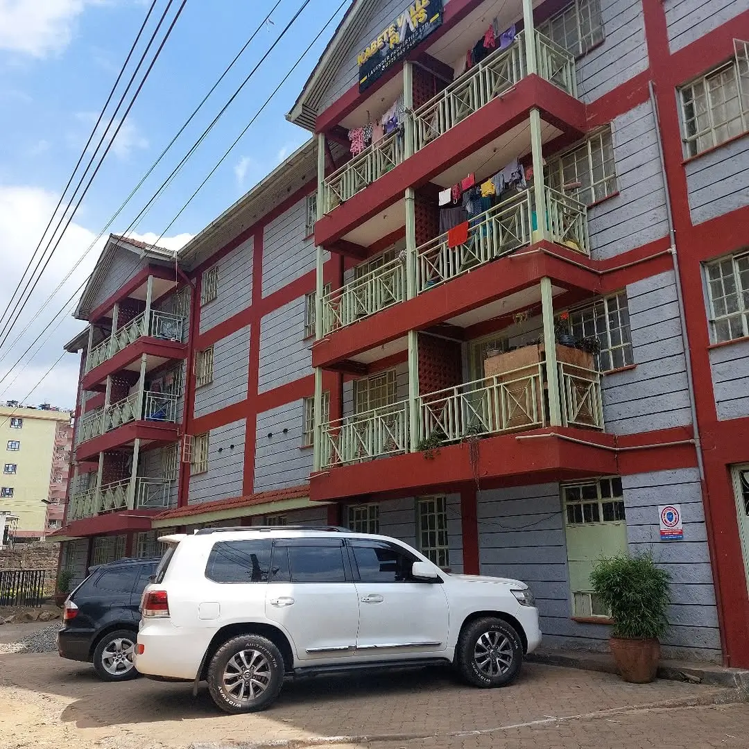 Multi-story residential building with red and white facade, balconies