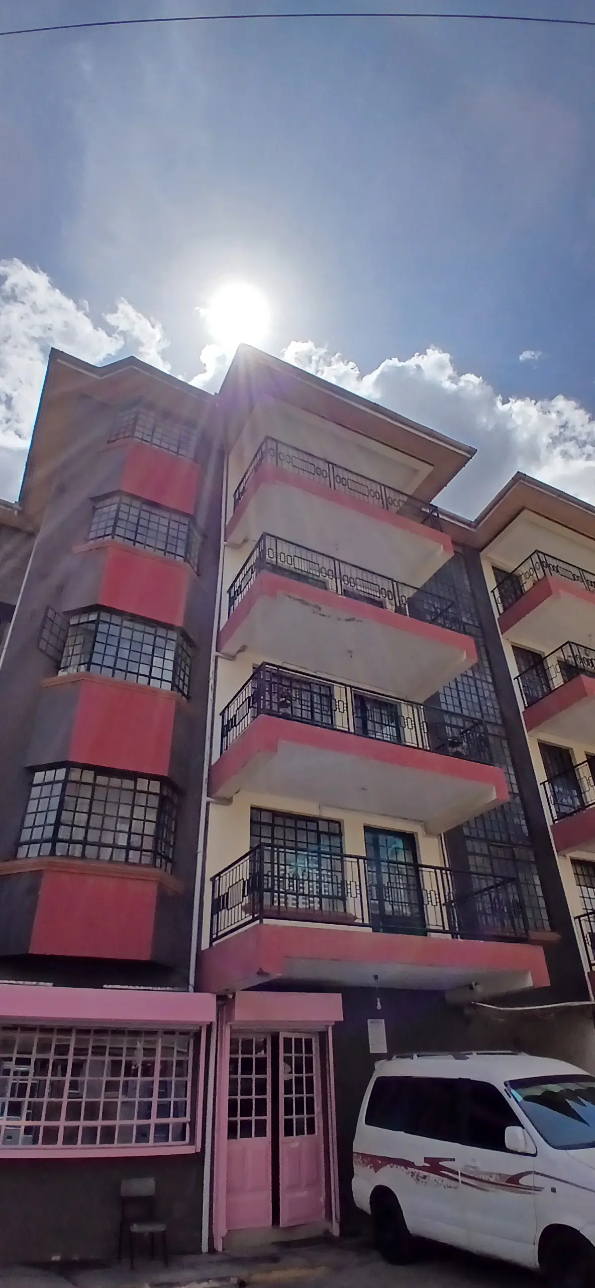 Multi-story residential building facade with red and pink balconies