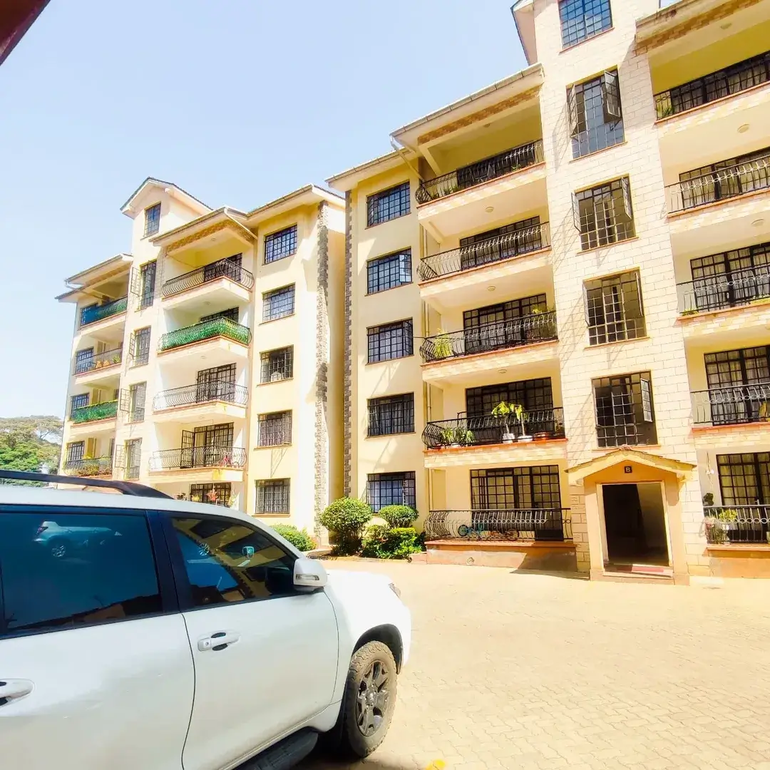 Multi-story residential building with yellow facade and parking compound