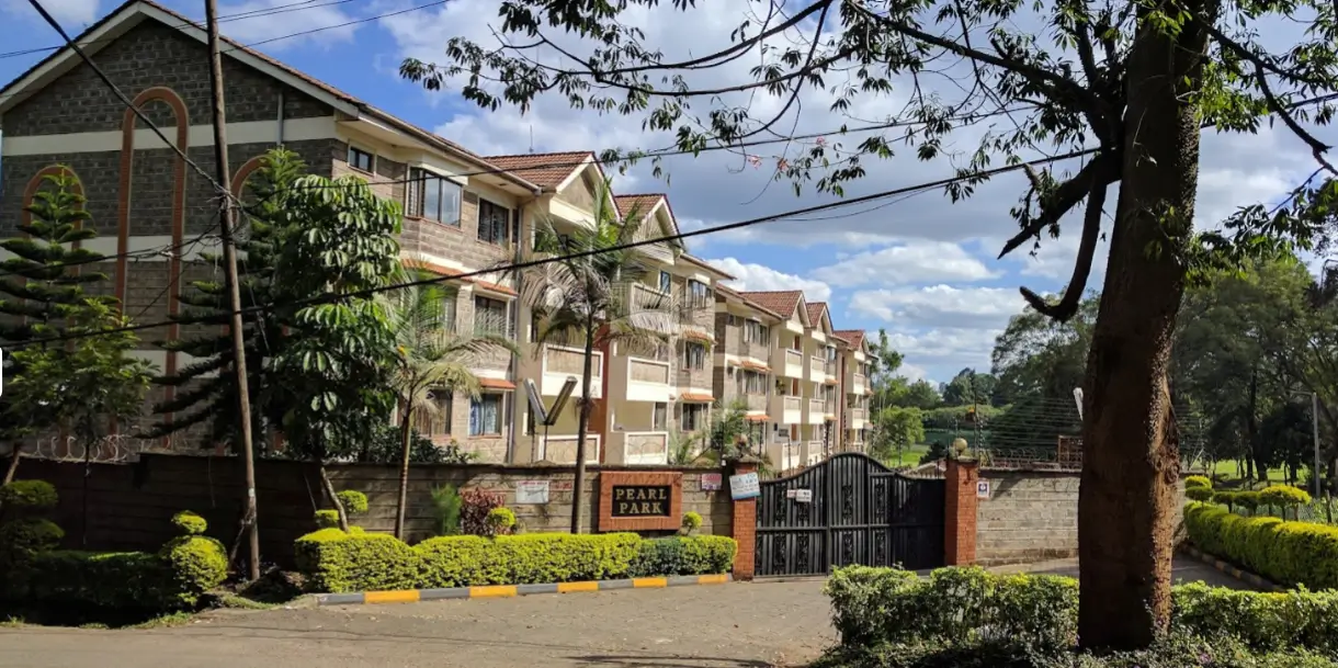 Multi-story residential building with manicured grounds and entry gate